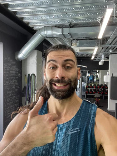 Smiling and Motivated Personal Trainer Assisting a Client with Fitness Training in a Well-equipped Gym